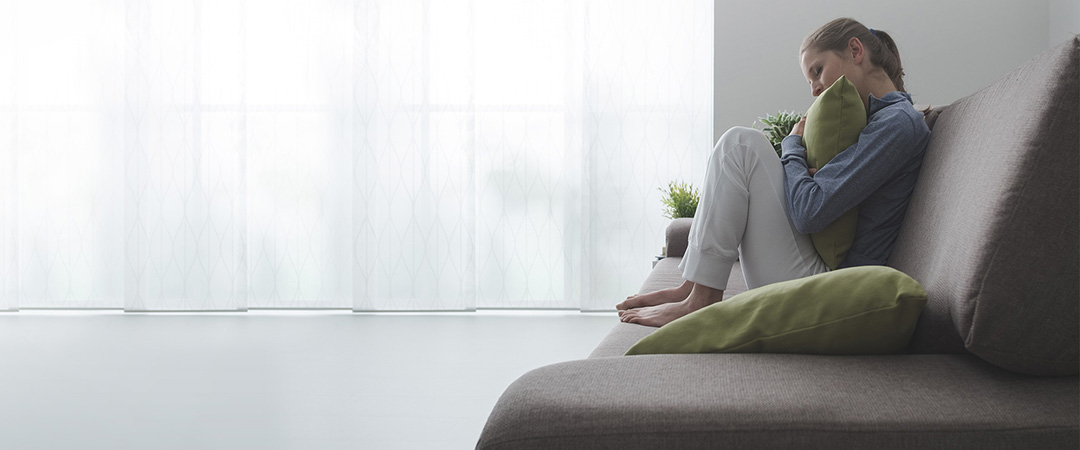 woman hugging a pillow seated on a couch