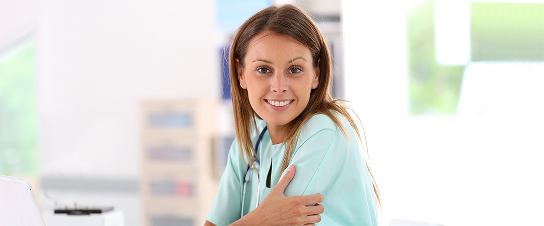 Young approachable nurse smiling and wearing a stethoscope around her neck.