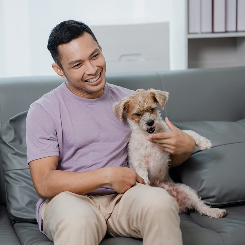 smiling man sitting on the couch with his small dog