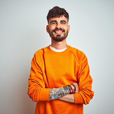 smiling man wearing a bright orange shirt and folding his arms